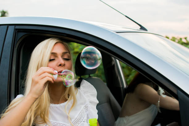 istock Woman blowing bubbles on road trip 1012773684