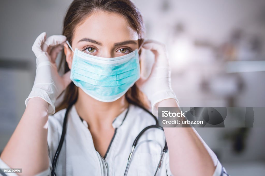 Female doctor with surgical mask on Young medical professional with procedure mask on her face Protective Face Mask Stock Photo