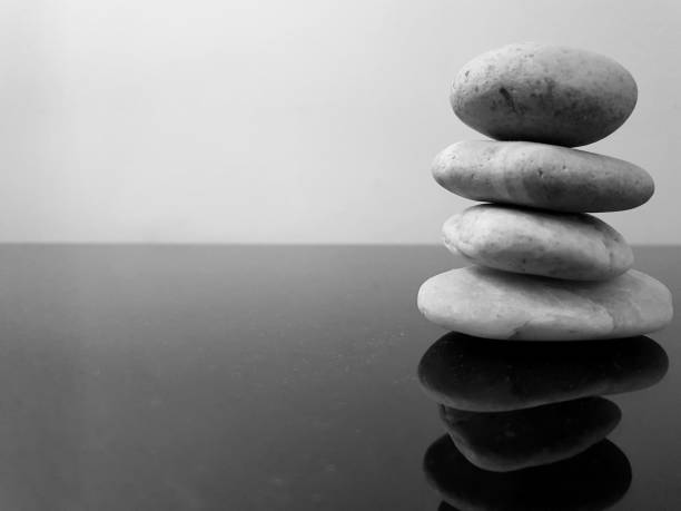 Balanced zen stones on a black table against grey background. Concept of harmony, balance and meditation, spa, relax. Copy space in black and white