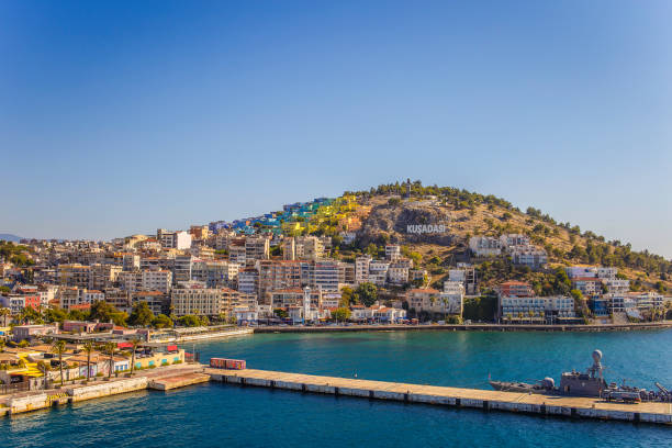 Beautiful city of Volos, Greece, by the Aegean sea's Pagasetic Gulf. Apartment buildings and a church are visible in the background and so are some unrecognizable people walking.