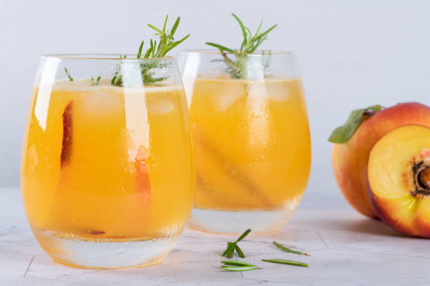 homemade peach juice with ice cubes and rosemary leaves in glass on marble stone background. - peach juice imagens e fotografias de stock