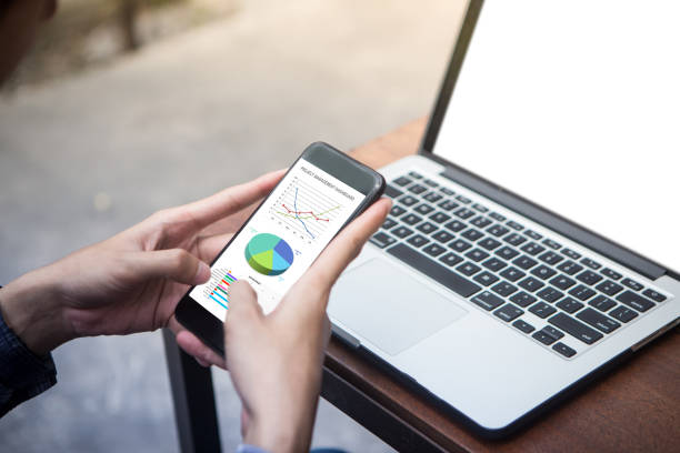 istock Man holding smartphone and review excel project dashboard summary result at outdoor cafe 1012823402