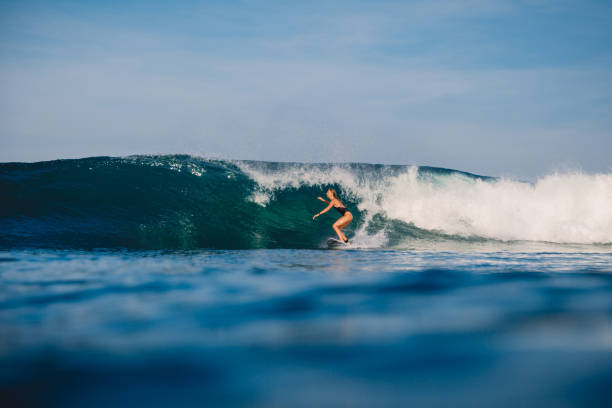 istock Surfer girl at surfboard and blue wave. 1012828582