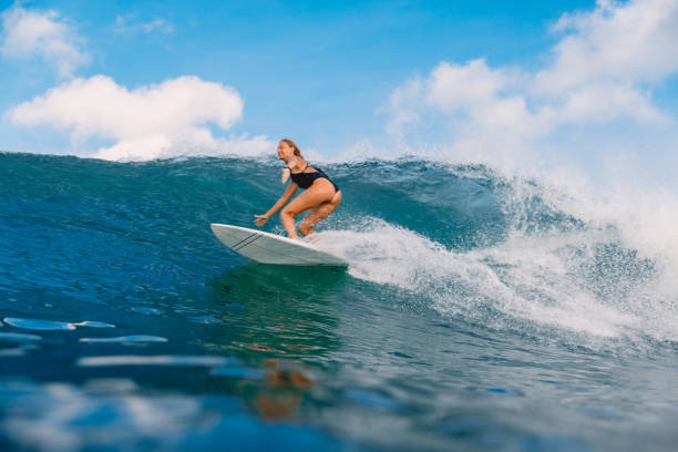 istock Beautiful surfer woman at surfboard on ocean wave. 1012830656