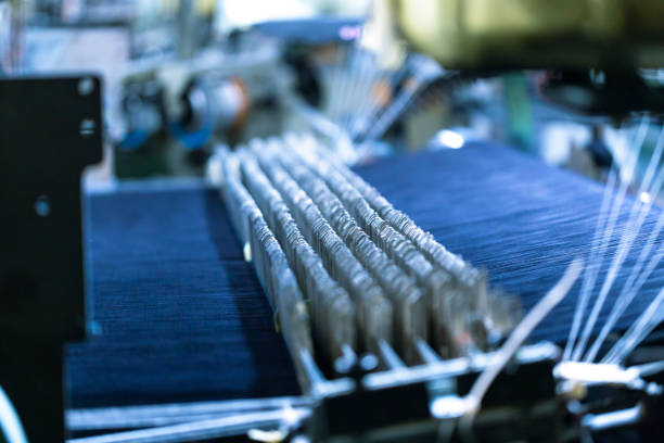 Seamstress cutting red fabric with scissors at workplace, closeup