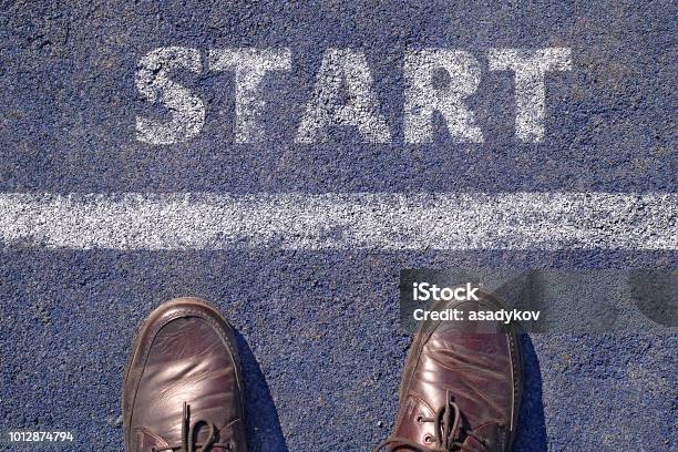 Man Feet In Brown Leather Shoes Standing Before Shabby Sign Start Written On Asphalt Top View Stock Photo - Download Image Now