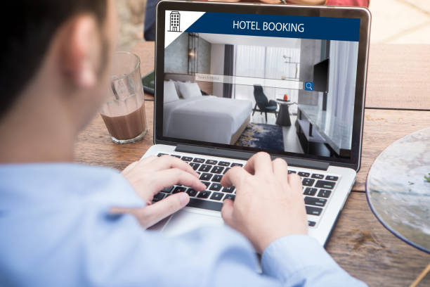 若い男は、ラップトップを使用してウェブサイトにホテルを予約オンライン web サービスを使用して宿泊施設を検索/屋外カフェでコンピューター - lodging ストックフォトと画像