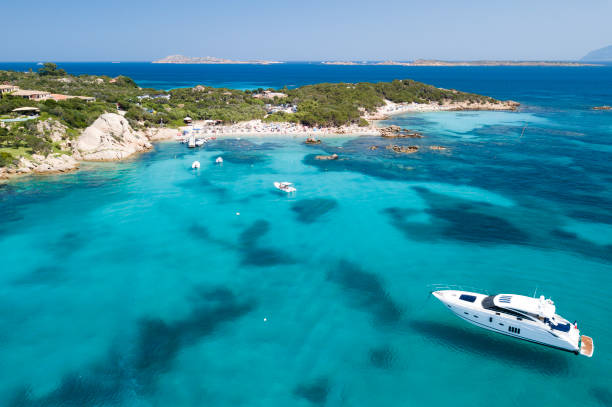 view from above, aerial picture of a yacht floating on the transparent and turquoise mediterranean sea. emerald coast (costa smeralda) in sardinia, italy. - inflatable raft nautical vessel sea inflatable imagens e fotografias de stock