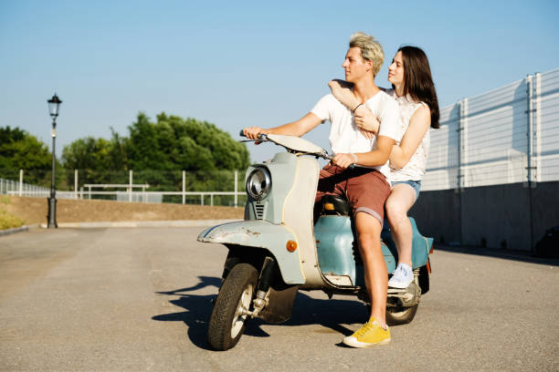 Young beautiful couple riding on old scooter