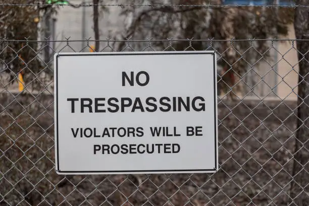 No Trespassing sign on metal mesh fence closeup