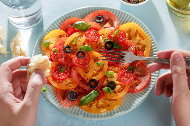 istock Man's hands eating homemade tomato carpaccio with bread and fork. 1013005148