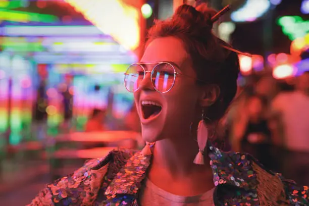 Photo of Woman wearing sparkling jacket on the city street with neon lights