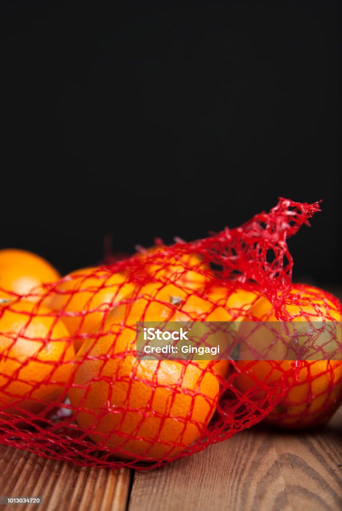 Citrus Fruits Tangerine in Oranges in plastic net bag package. no plastic concept. Packaging that does not recycle. Plastic. Rustic wooden background. Citrus Tangerine in Oranges in plastic net bag package. no plastic concept. Packaging that does not recycle. Rustic wooden background. Agriculture Stock Photo