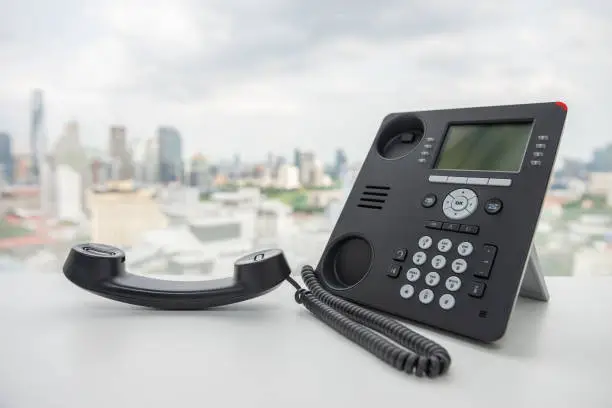 Black IP Phone on the white table with city scape background