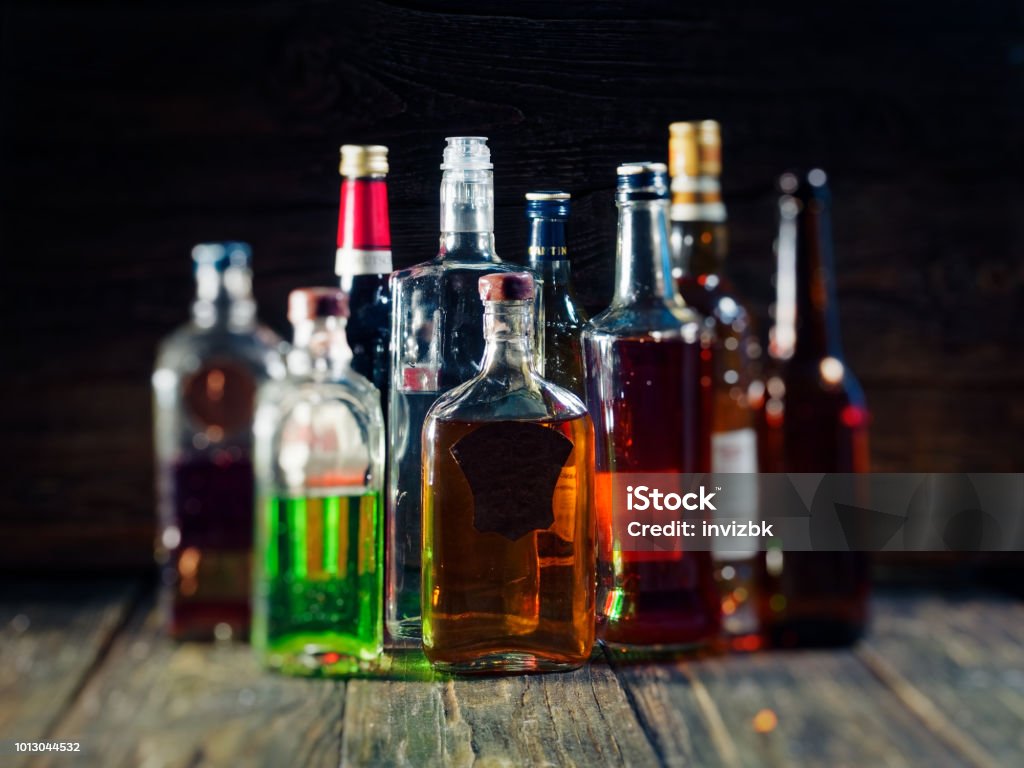 Bar counter Group of various bottles of alcohol on the wooden bar counter Alcohol - Drink Stock Photo