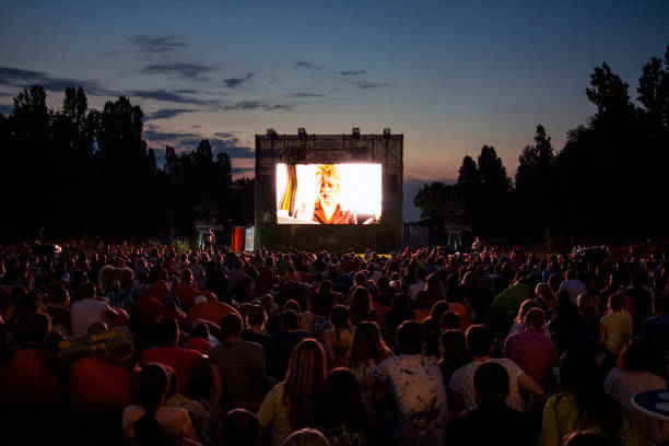 open air cinema 02 August 2018-Bucharest, Romania. People waiting and watching in the public park Herastrau for the movie to start on the projection screen of the open air cinema features stock pictures, royalty-free photos & images