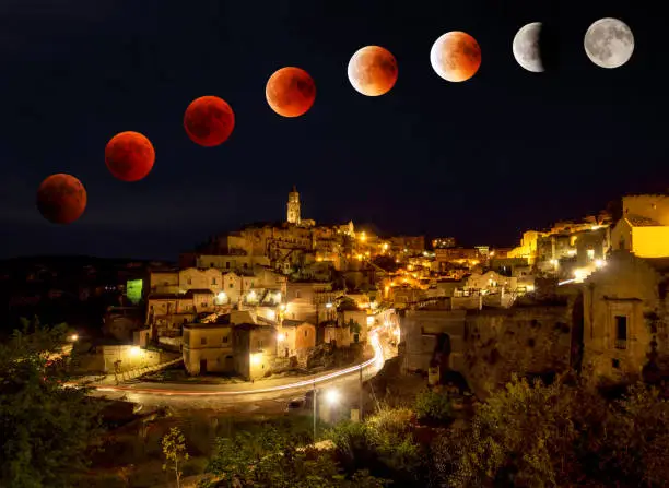 The longest moon eclipse of the century with the phenomenon of Red Moon seen from the enchanted old theater in stone of Sassi di Matera, with multiple exposure.