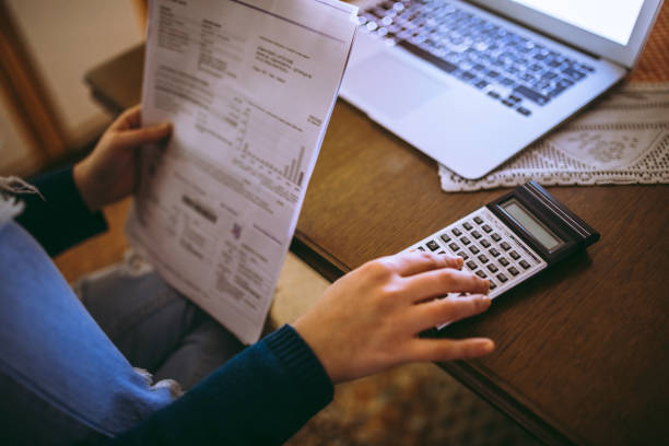 istock Woman calculating bills with calculator 1013074232