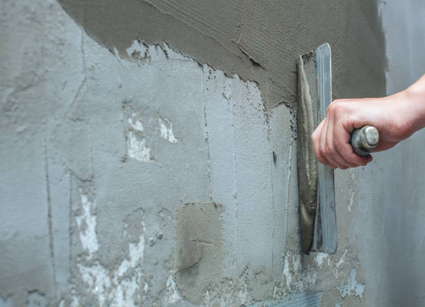 istock Builder puts mortar trowel wall. Plaster walls. 1013074660