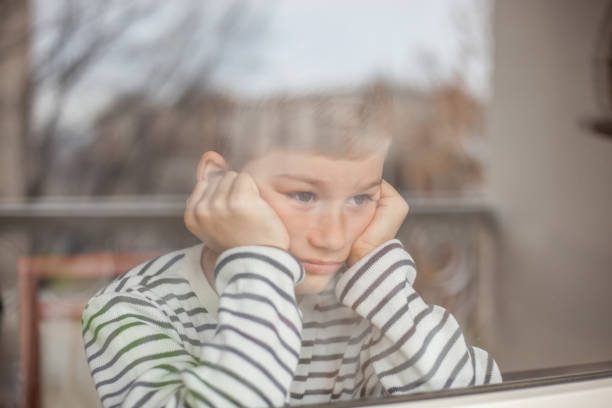 chico aburrido busca a través de la ventana - sadness teenager little boys depression fotografías e imágenes de stock