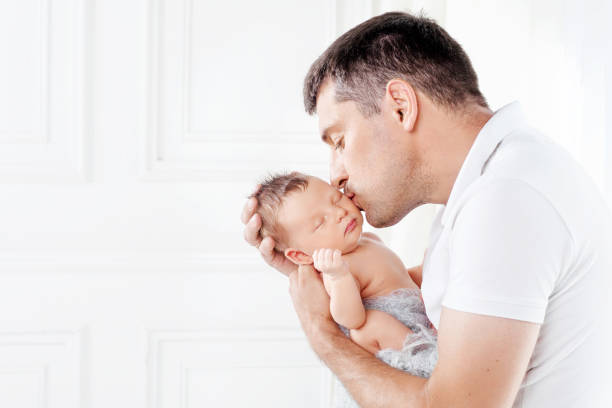 Father holding his newborn baby in  hands. Father kissing his baby stock photo