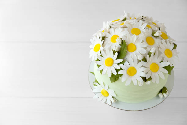 istock Cake decorated with chamomile flowers from mastic on a white wooden table. 1013094664