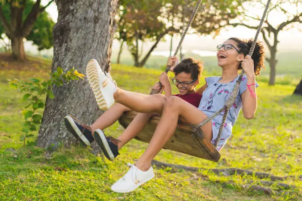 Photo of Happy siblings playing on the swing