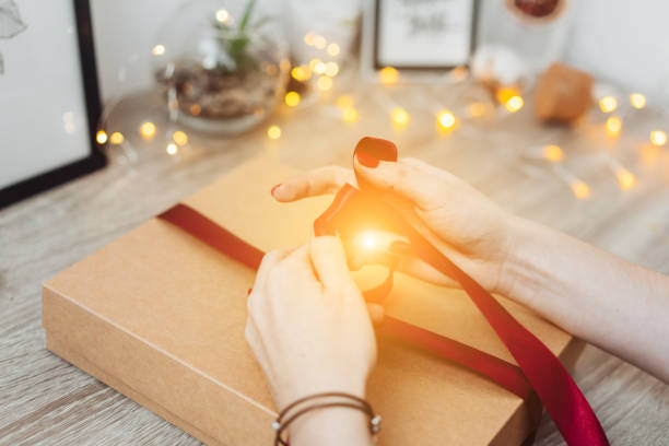 istock Woman wrapping present in paper with red ribbon. 1013106214