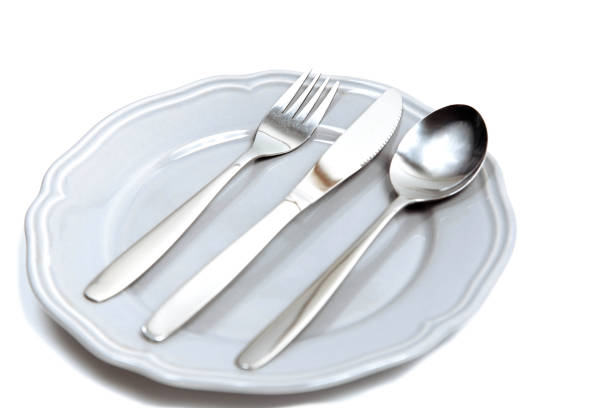 istock Plate with a silver fork, spoon and a knife isolated on white background 1013111782