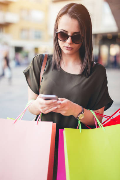 istock Young woman walking after shopping and using a mobile phone. 1013115874
