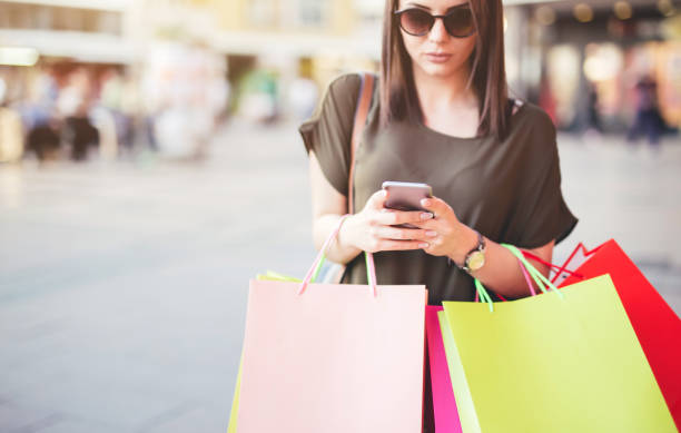 istock Young woman walking after shopping and using a mobile phone. 1013116198