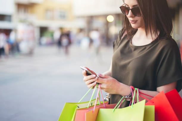 istock Young woman walking after shopping and using a mobile phone. 1013120462