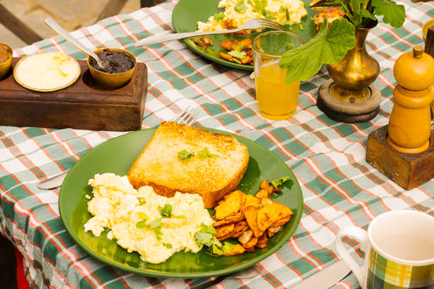 A breakfast meal with a toasted bread, scrambled eggs and grilled potatoes in a plate with checkered table cloth. A breakfast meal with a toasted bread, scrambled eggs and grilled potatoes in a plate with checkered table cloth. hash brown stock pictures, royalty-free photos & images