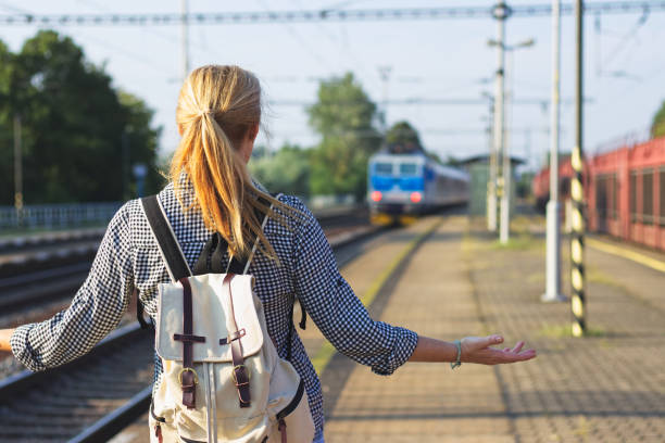Woman standing on railroad station and looking to leaving train. Traveler is worried, because she missed a train stock photo