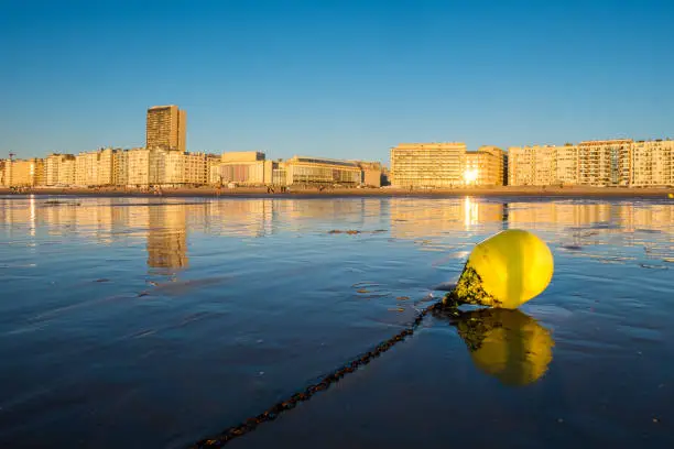 Bright yellow buoy on the beach of Oostende with city skyline in the background, Thursday 2 August 2018, Oostende, Belgium