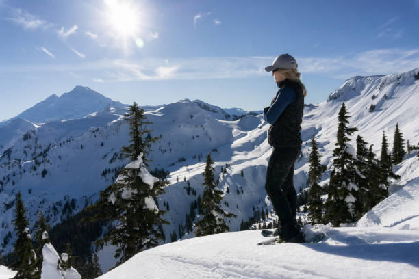 Snowshoeing in the Snow Adventurous woman is snowshoeing in the beautiful mountainous landscape. Taken in Artist Point, Northeast of Seattle, Washington, United States of America. mt baker stock pictures, royalty-free photos & images