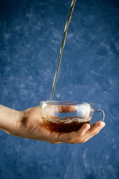 istock Woman's hand holding glass cup with pouring tea, selective focus 1013213322