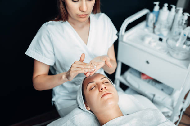 istock Beautician hands with cream against patient face 1013213420
