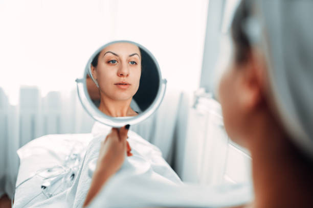 istock Patient looks at her face through the mirror 1013213484