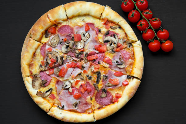 istock Freshly baked pizza on black background, view from above. Flat lay, overhead, top view. Closeup. 1013219202