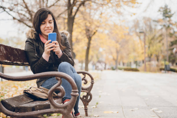 istock Woman texting on a park bench 1013241394