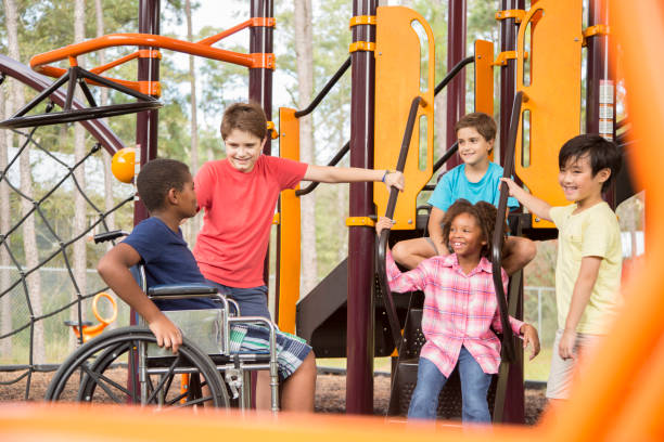 wieloetniczna grupa uczniów na szkolnym placu zabaw, jeden wózek inwalidzki. - child jungle gym playground laughing zdjęcia i obrazy z banku zdjęć