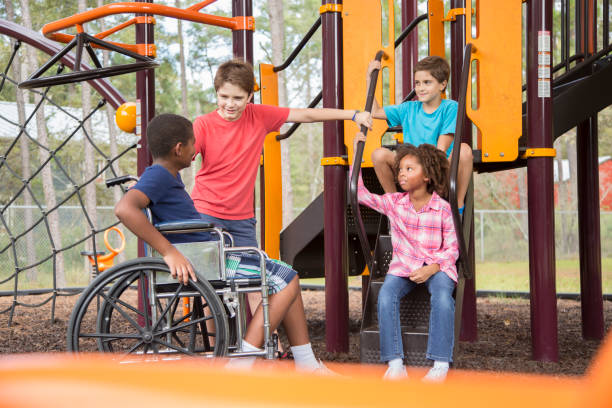 multi-ethnic group of school children on school playground, one wheelchair. - child jungle gym playground laughing imagens e fotografias de stock