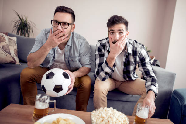 istock Two young caucasian men watching a soccer game at home 1013286320