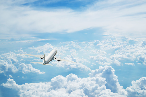 Back view of commercial airplane flying above clouds. Copyspace for text
