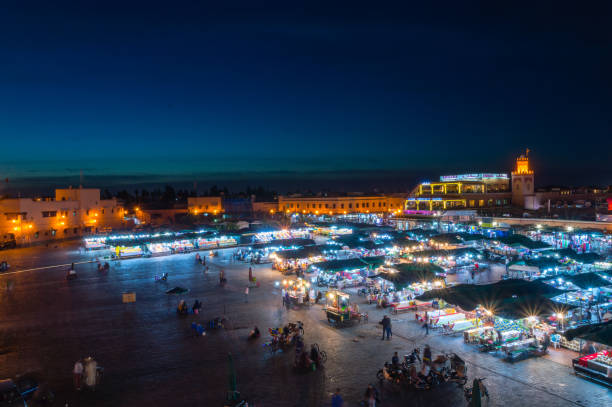 place jemaa el-fna pendant la nuit, en regardant vers le café argana et le souk couvert. - djemaa el fnaa photos et images de collection