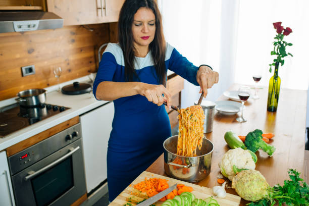 Happy Joyful Mother Cooking A Pasta. Healthy Food Concept. stock photo