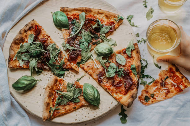 flat lay of homemade delicious pizza and beer on wooden board over white tablecloth background stock photo
