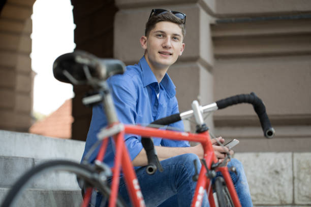 istock Cute young guy with bicycle, sitting and using phone 1013342630