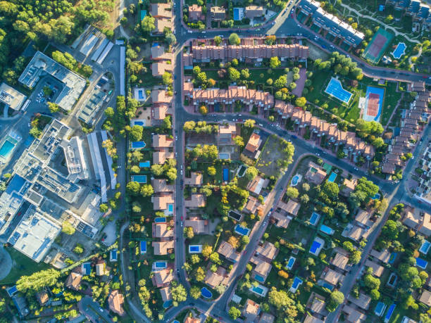an aerial view from the drone of a neighborhood with its swimming pools inside a forest in the outskirts of madrid city seeing the urban planning of the area with its home and streets aligned - madrid built structure house spain imagens e fotografias de stock